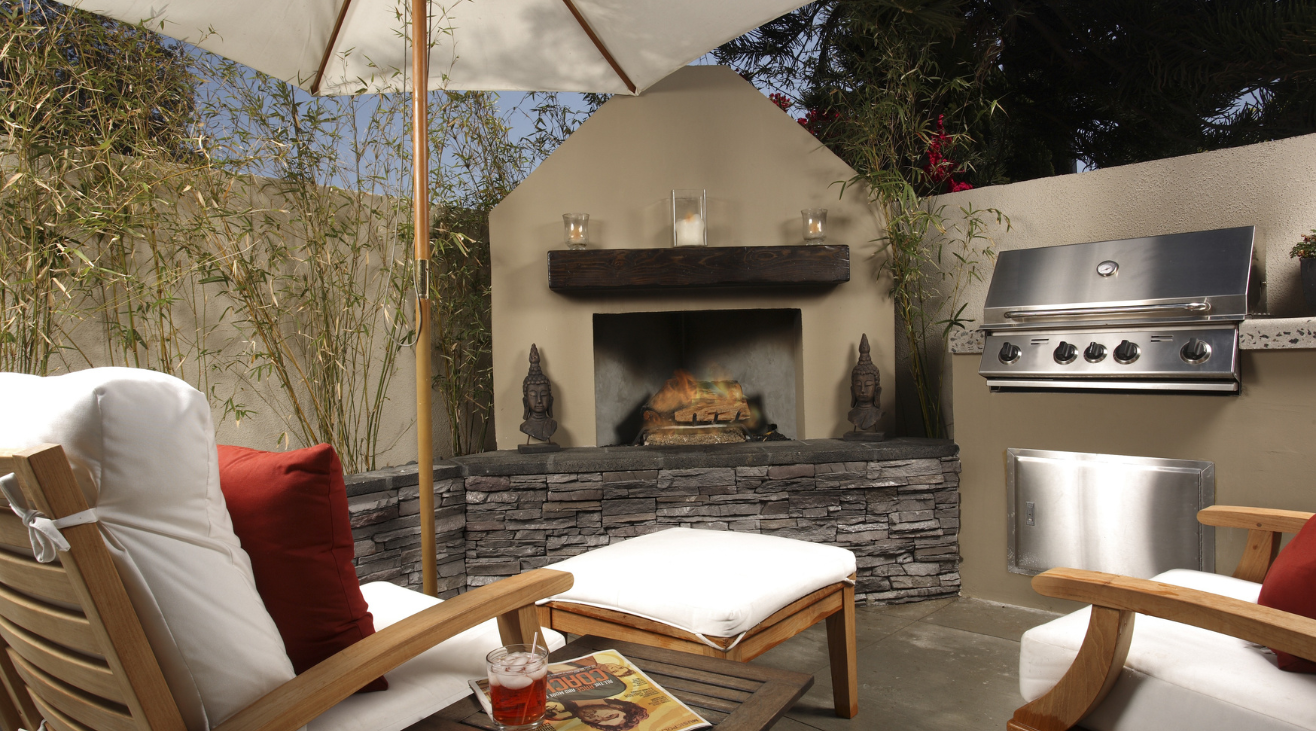A patio with chairs and an umbrella and a fireplace