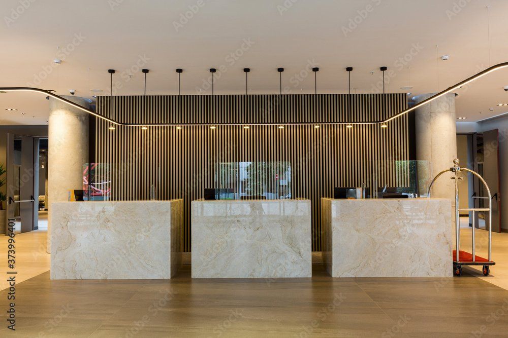A hotel lobby with three reception desks and a luggage cart.