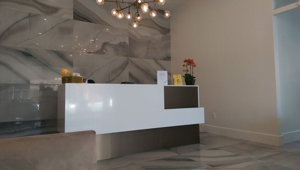 A white reception desk with a chandelier hanging from the ceiling