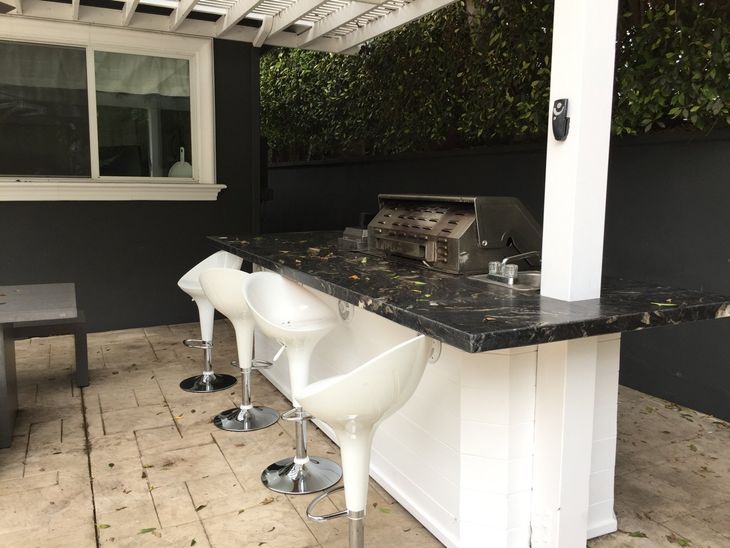A bar with stools and a grill under a pergola