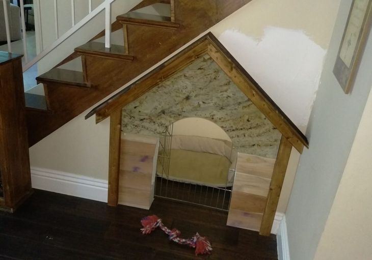 A dog house is under a set of stairs