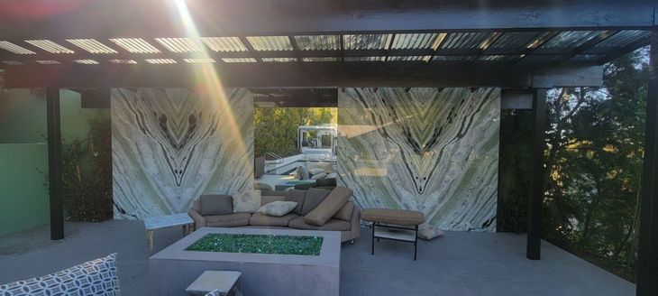 A patio with a fire pit and a couch under a pergola.