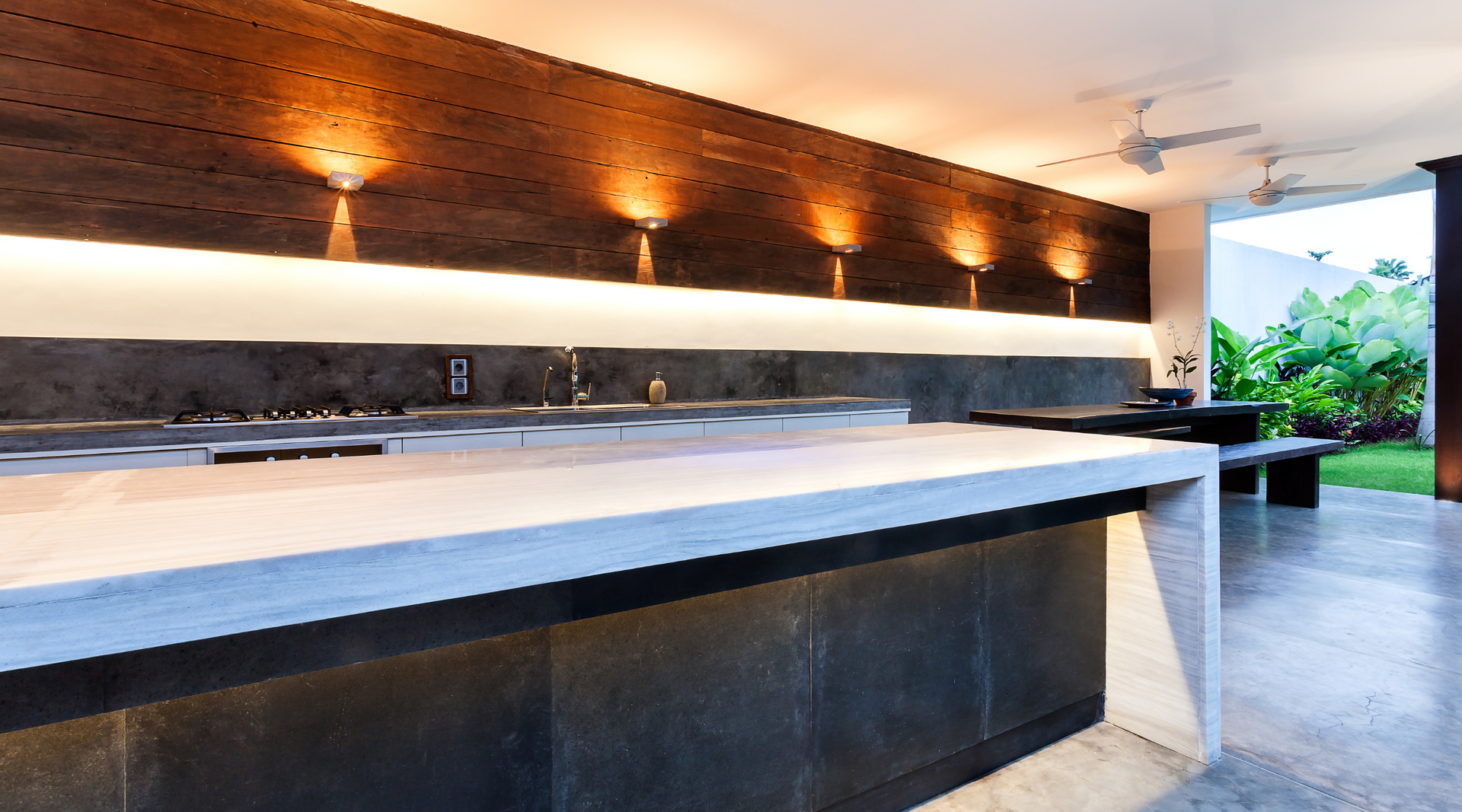 A kitchen with a concrete counter top and a wooden wall