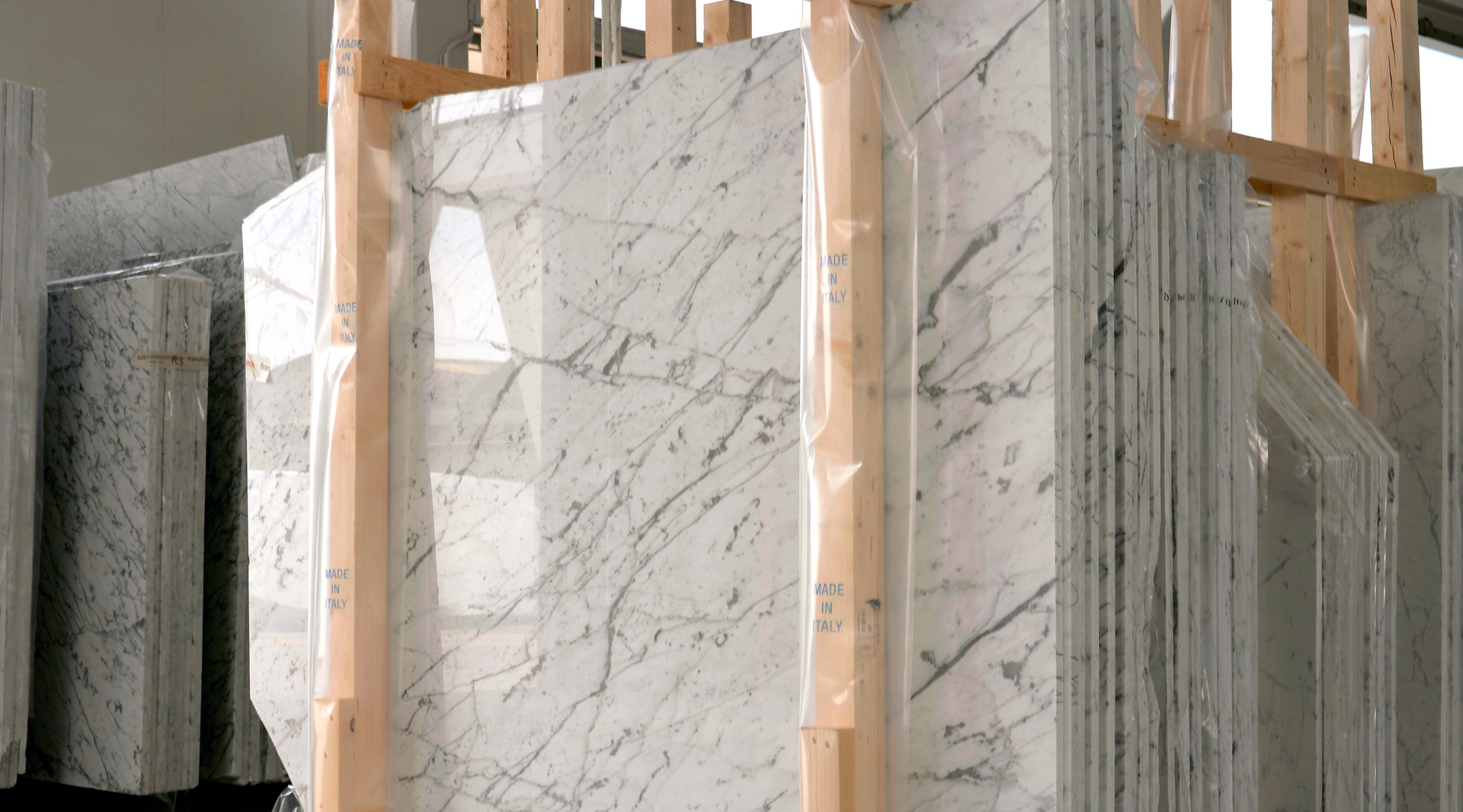 A stack of white marble slabs sitting on top of each other on a wooden rack.