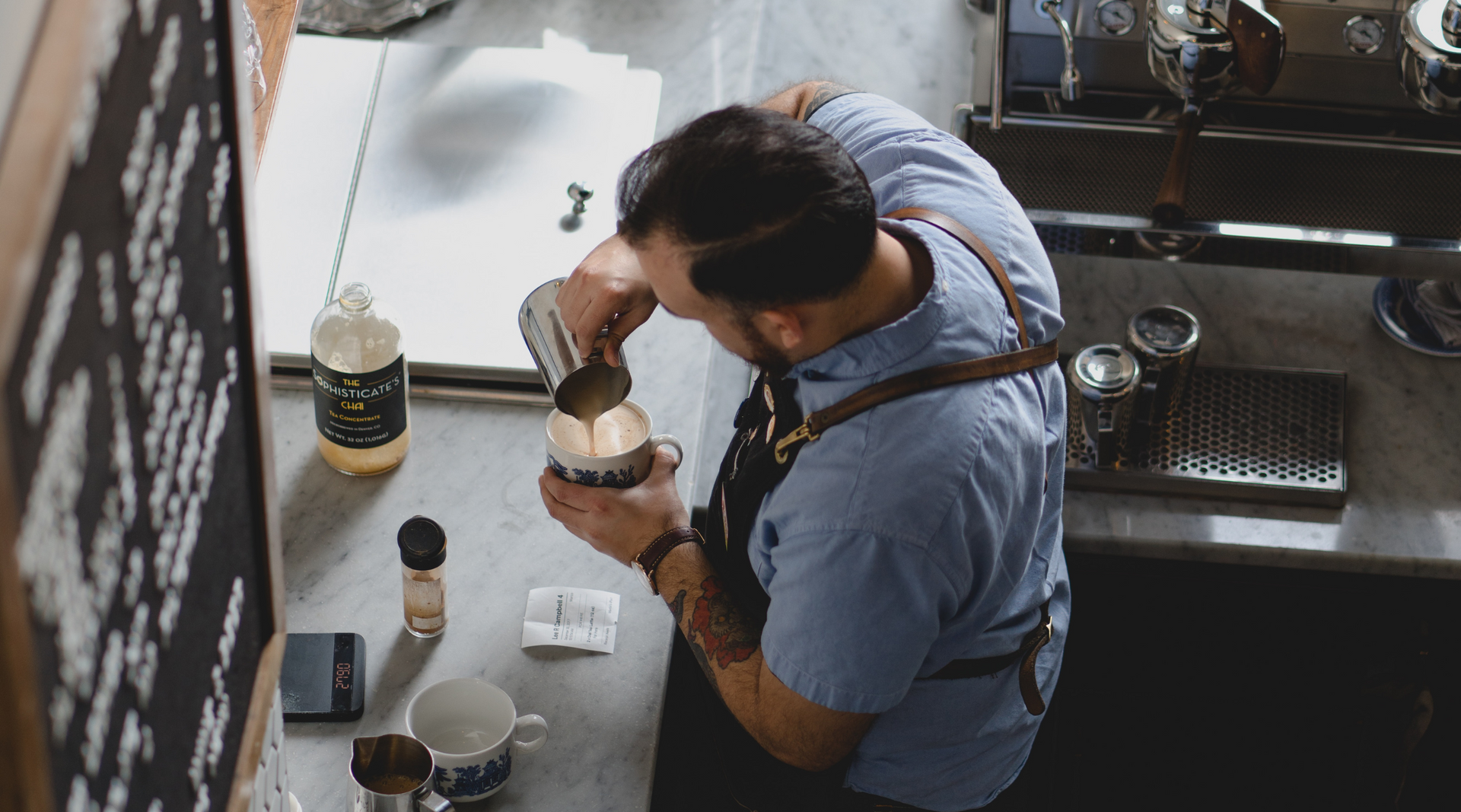 A man is pouring milk into a cup of coffee.