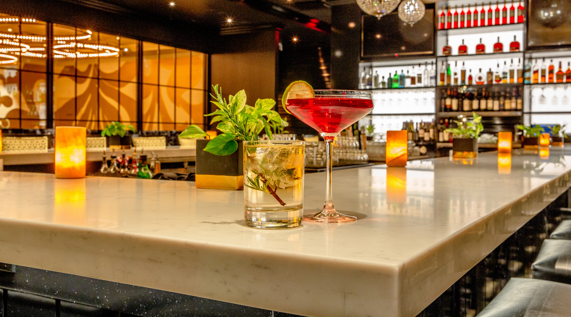 A bar with a martini and a glass of water on the counter.