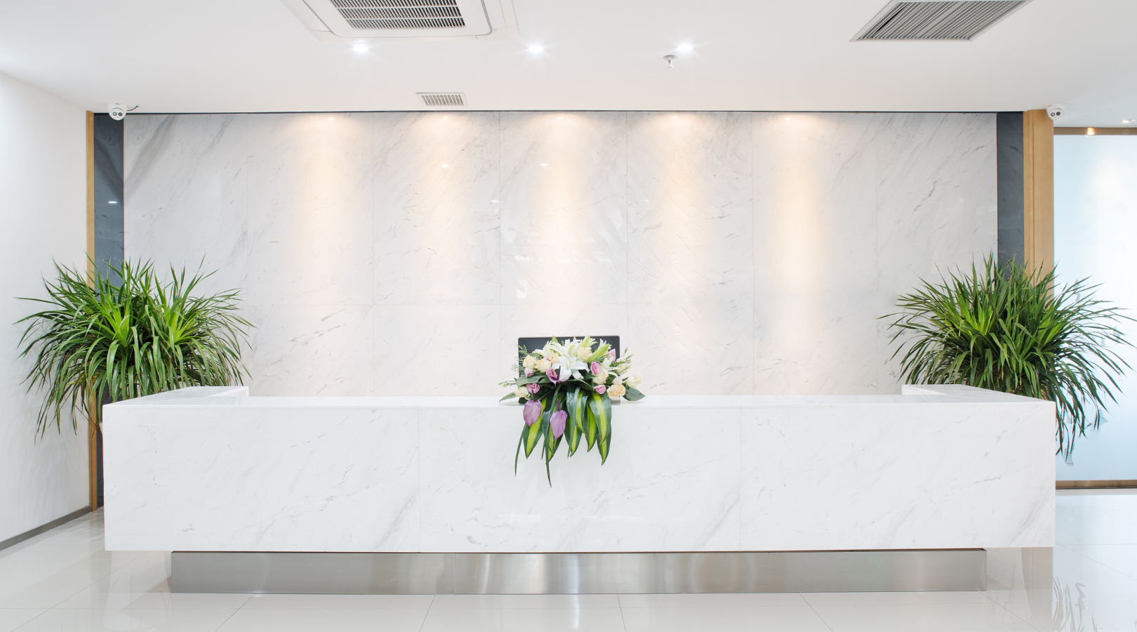 A white reception desk with flowers on it in an office.