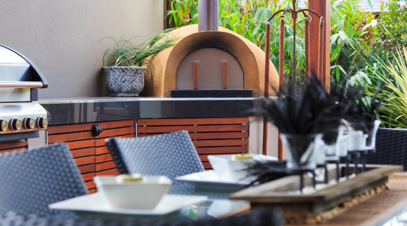 A patio with a table and chairs and a pizza oven