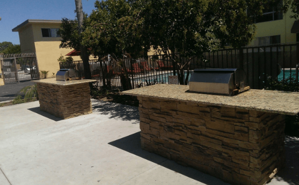 Two grills are sitting on a sidewalk next to a pool.