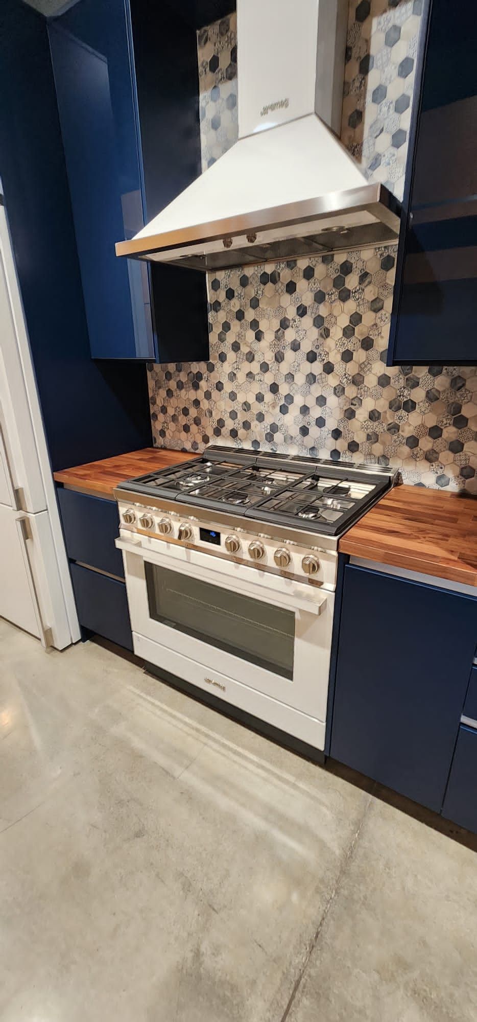 A kitchen with a stove and a hood above it.