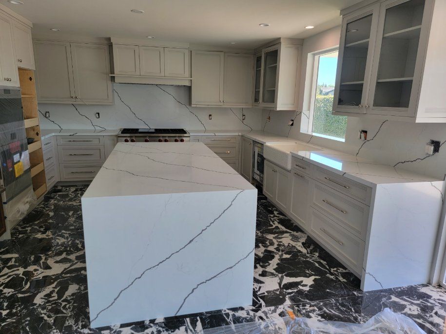 A kitchen with white cabinets and a large island in the middle.