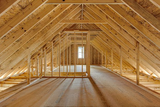 Unfinished wooden attic framing with exposed rafters and a small window