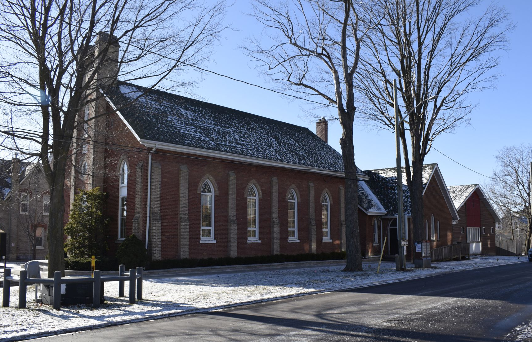 Red brick gothic revival church with tall arched windows on a snowy street