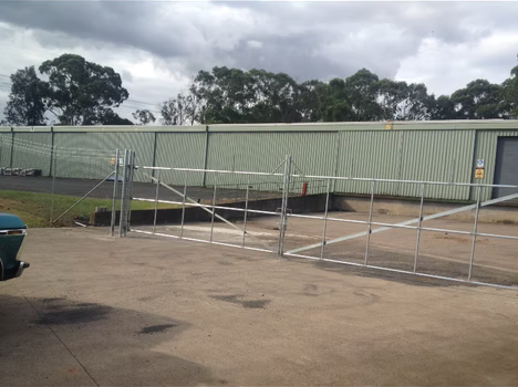 Metal ramp and temporary fencing in a parking lot with trees in the background