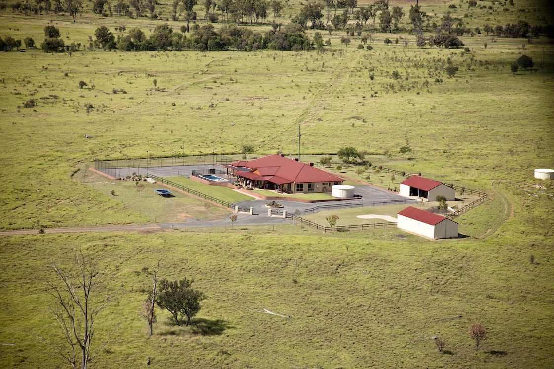 An aerial view of a house in the middle of a grassy field.
