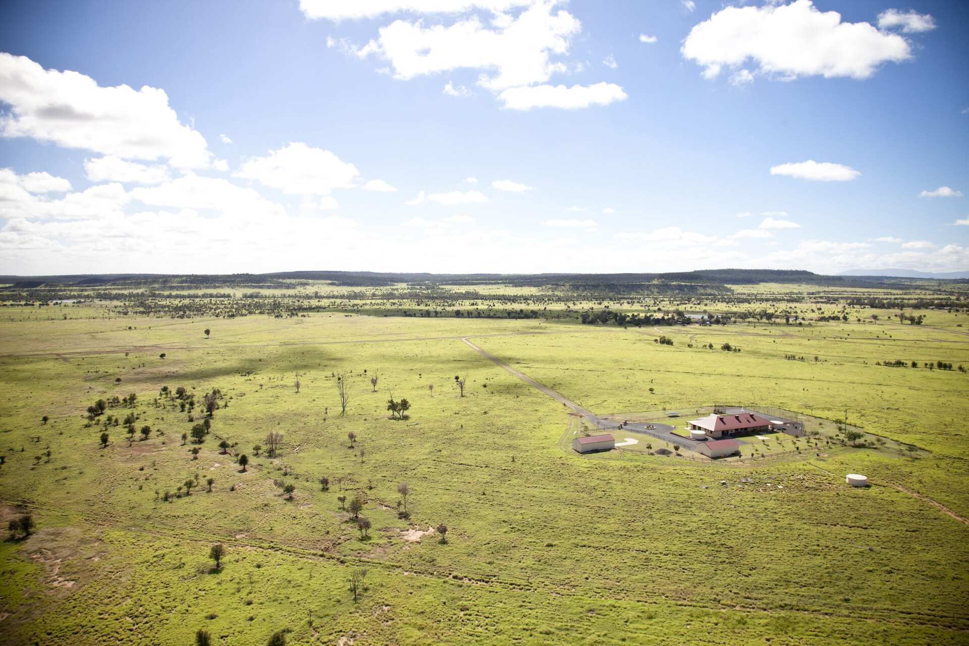 An aerial view of a grassy field with a house in the middle