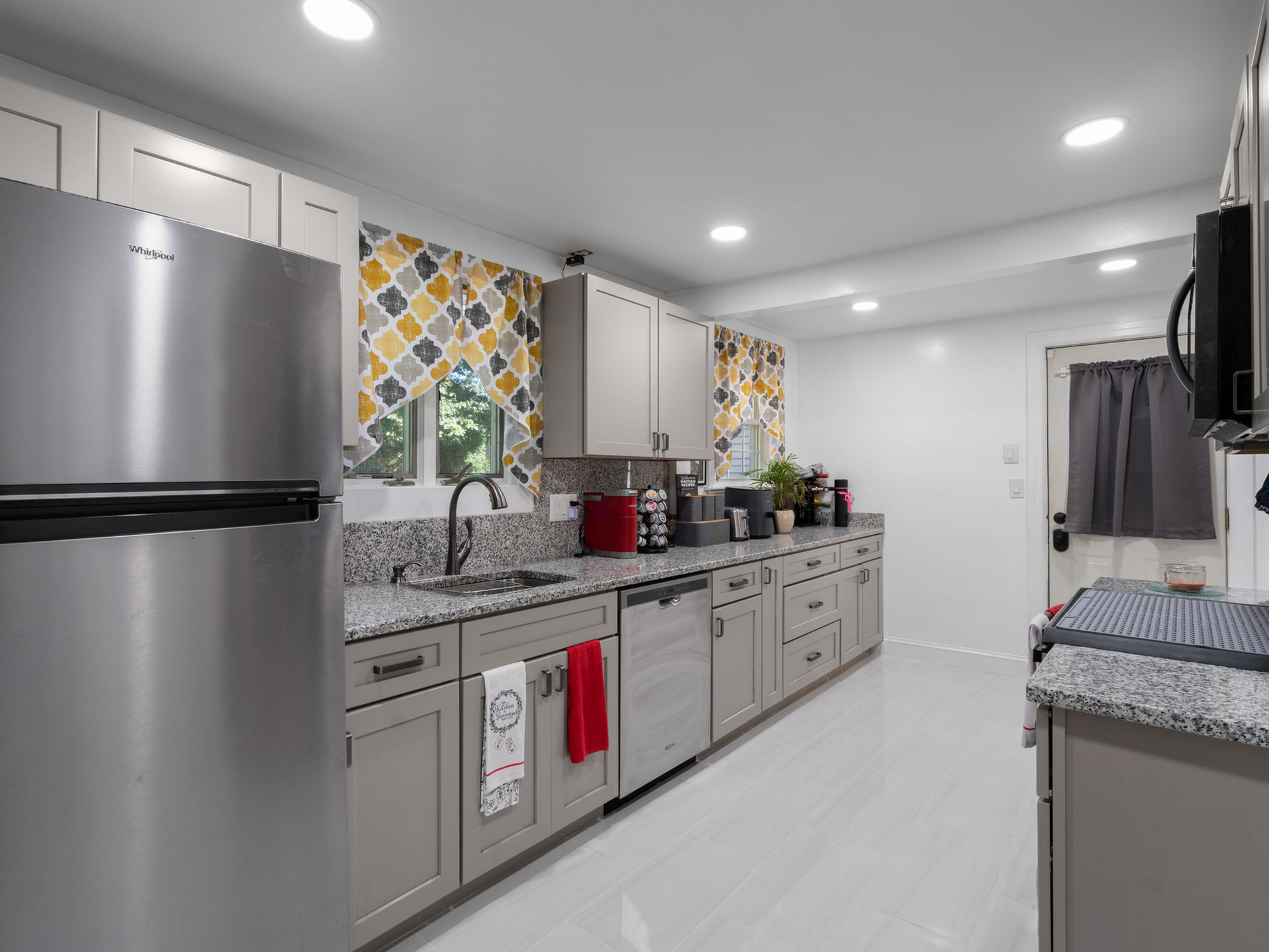 A kitchen with stainless steel appliances , granite counter tops , and gray cabinets.