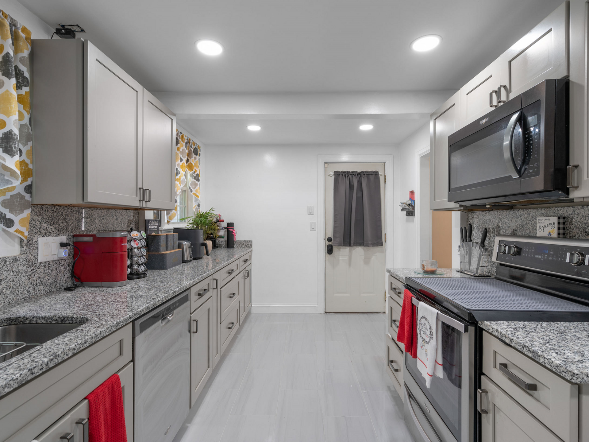 A kitchen with granite counter tops , stainless steel appliances , and white cabinets.