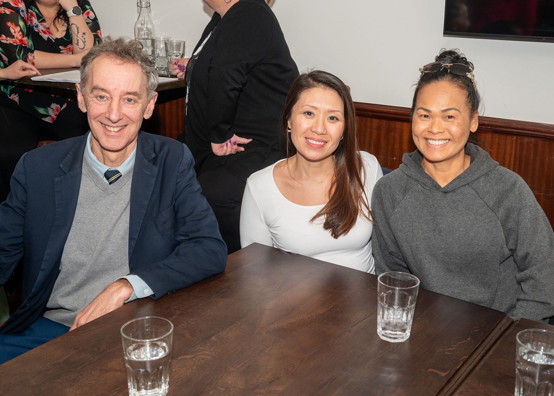 A man and two women are sitting at a table with glasses of water.