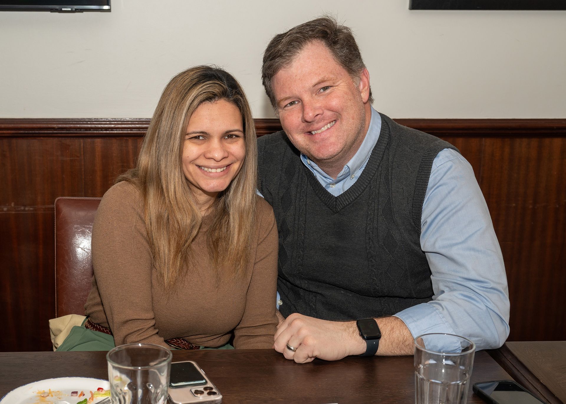 A man and a woman are posing for a picture while sitting at a table.