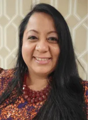 A woman with long black hair is smiling and wearing a necklace.