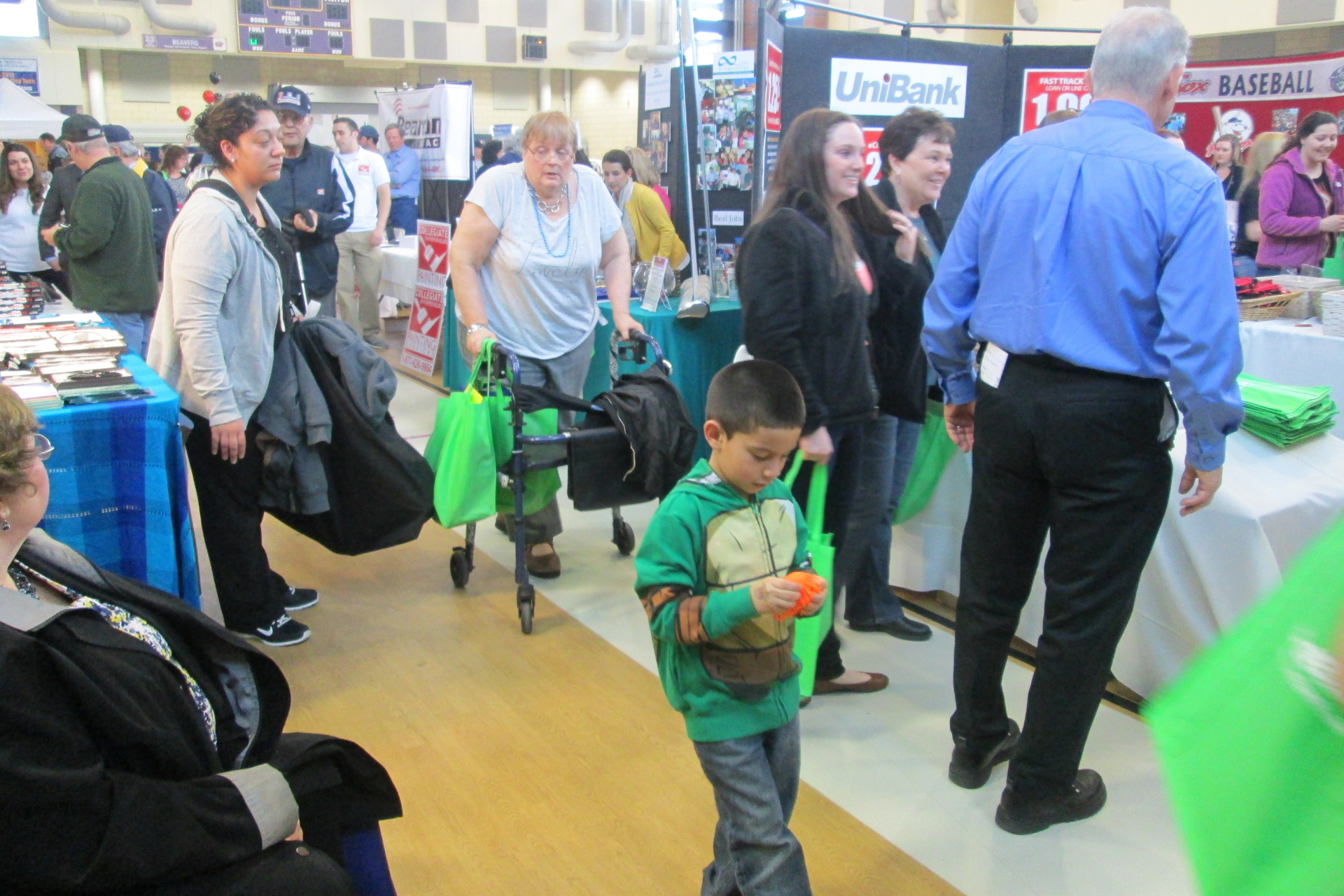 A boy in a green shirt is walking through a crowd of people
