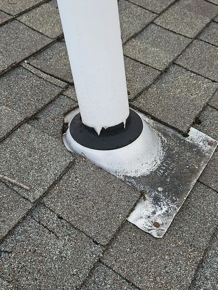 A white pipe is sitting on top of a brick roof.