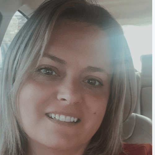 A woman is smiling while sitting in a car.