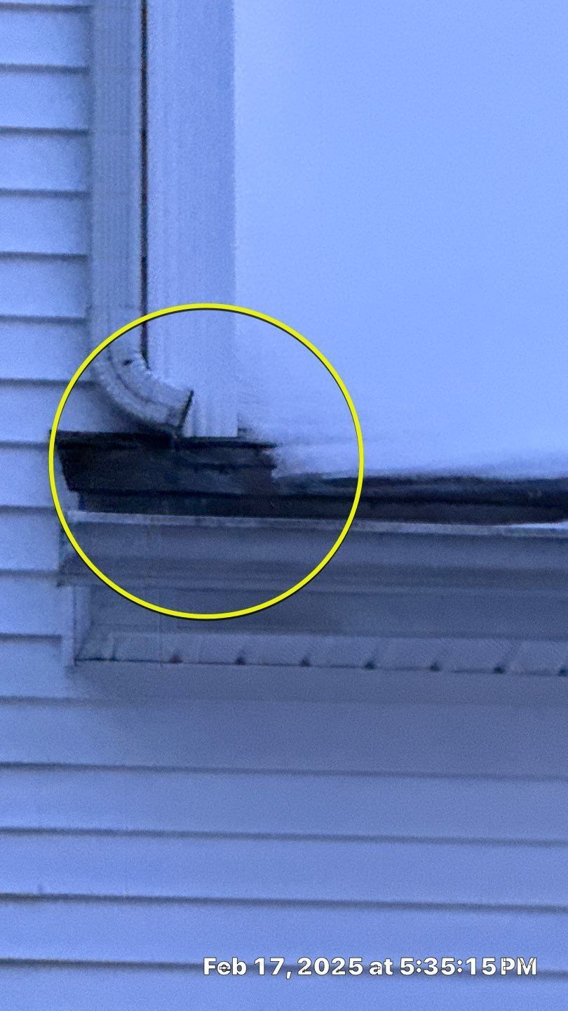 Yellow circle highlights a section of a building's gutter and a downspout. The gutter is covered in dark discoloration, likely from ice melt.