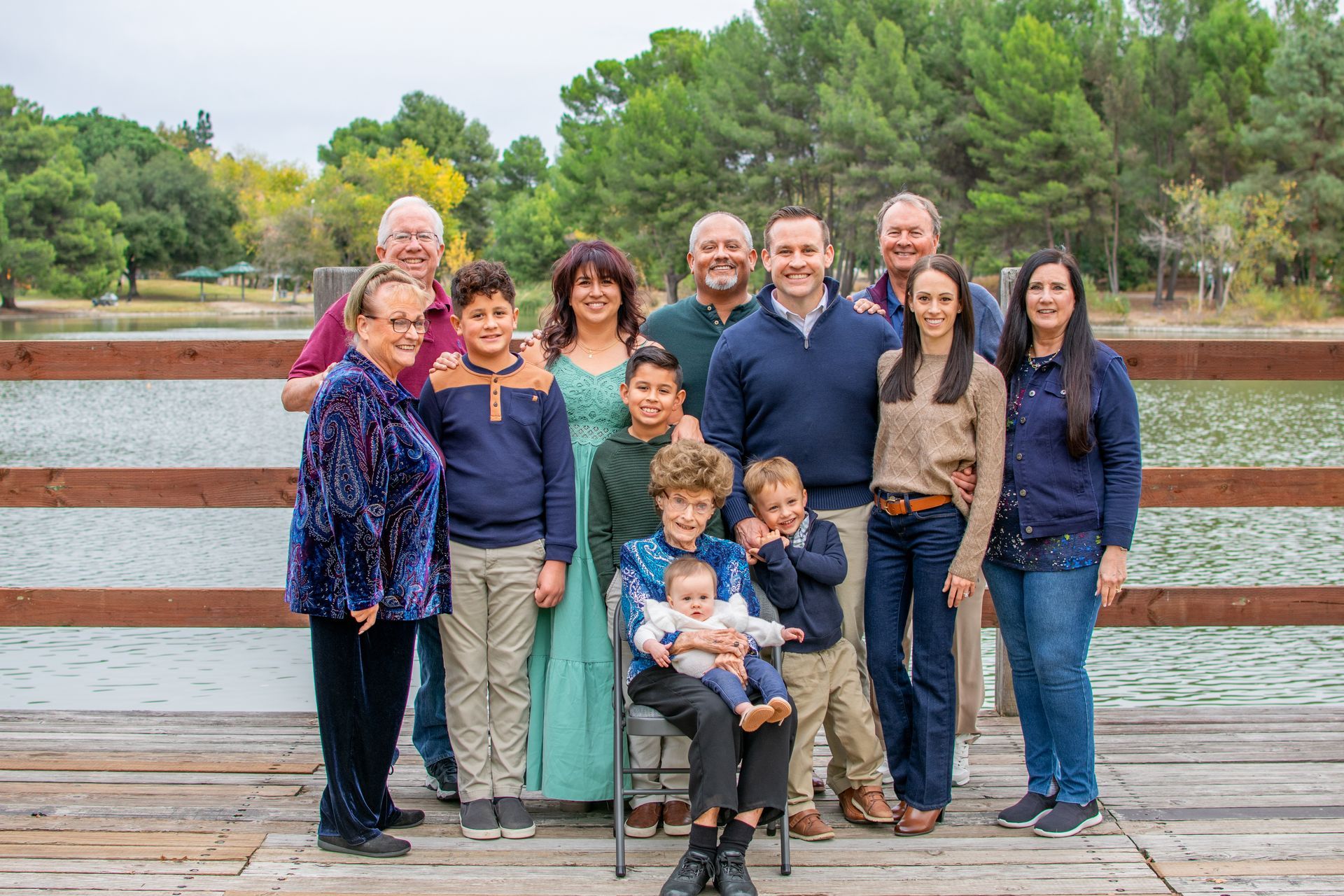 A large family is posing for a picture on a wooden dock. Generational Family photo