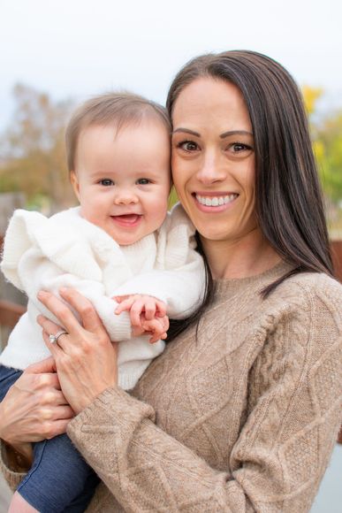 A woman is holding a baby in her arms and smiling at Yorba Regional Park.