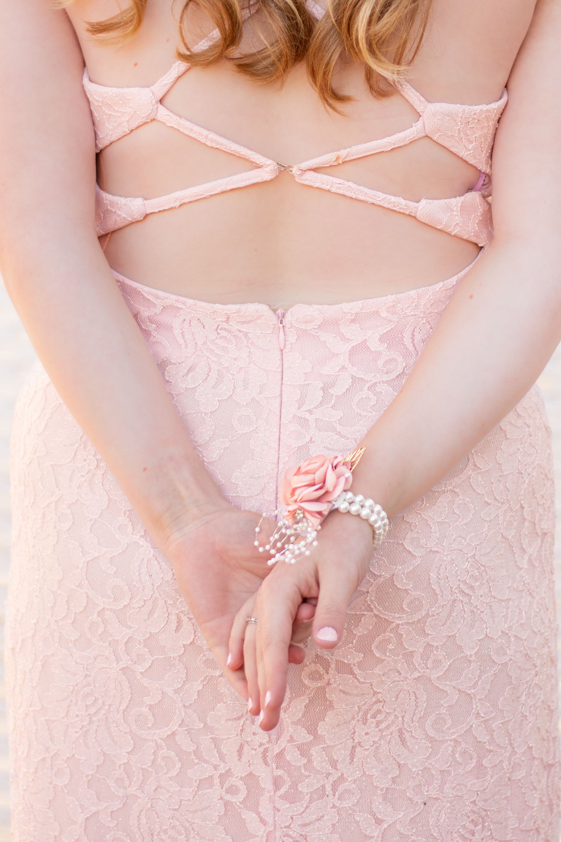 A woman in a pink dress is holding her hands behind her back in the South Bay