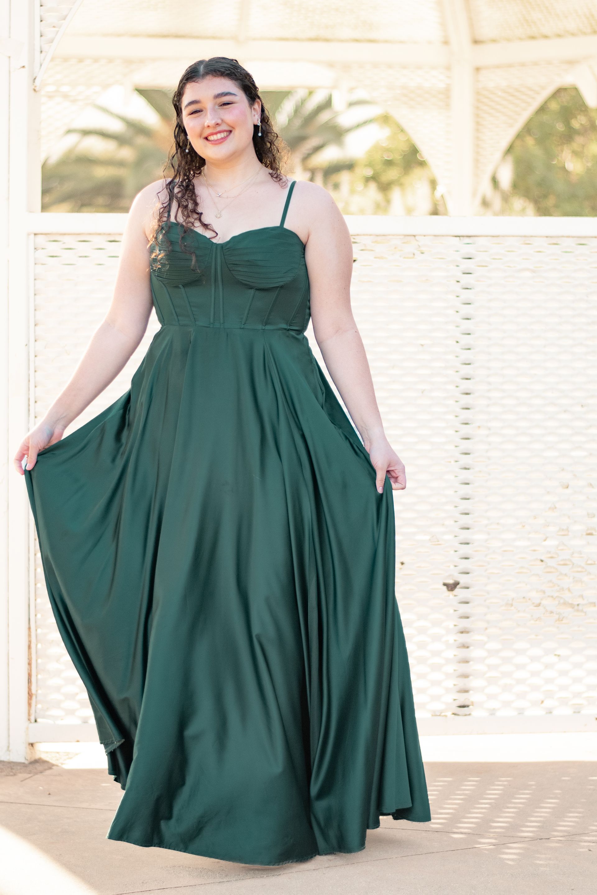 A woman in a green dress is standing in front of a white building in Coastal San Pedro, CA