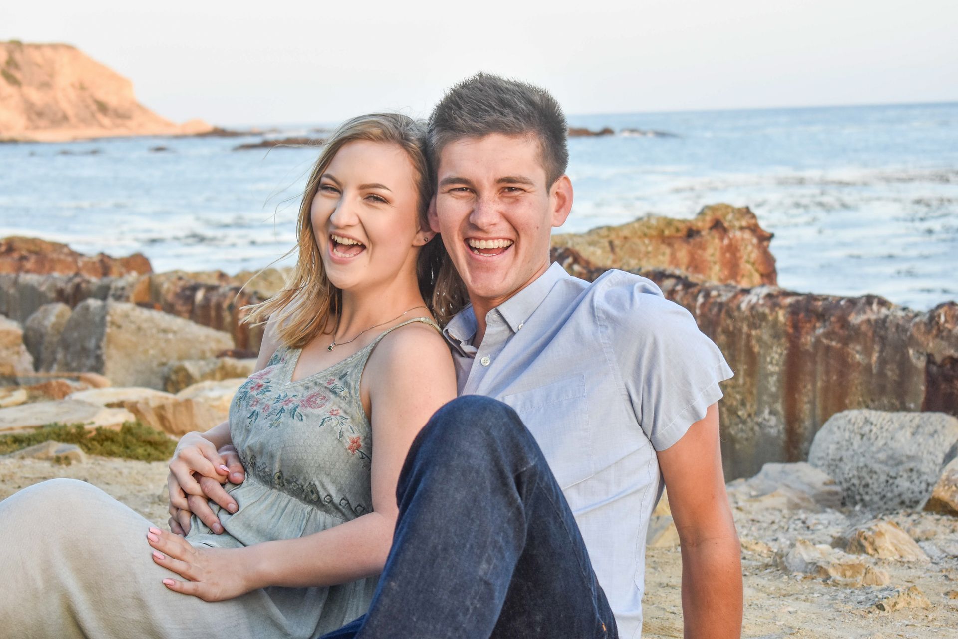 A man and a woman are standing next to each other on a rocky beach.