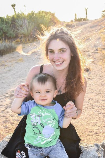 A woman is sitting on a rock holding a baby. Family