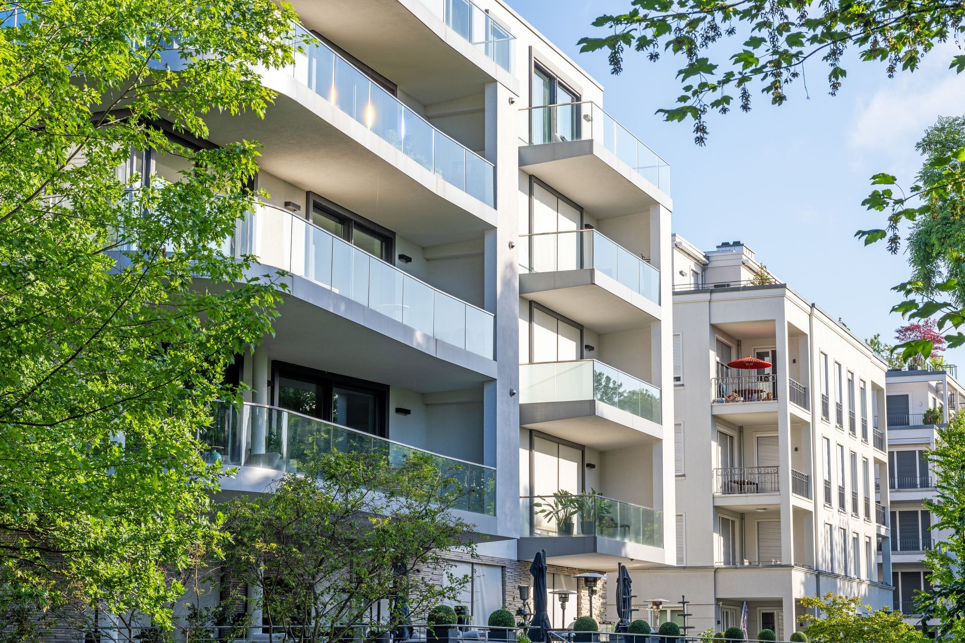 Modern apartment buildings with balconies and trees along a sunny street
