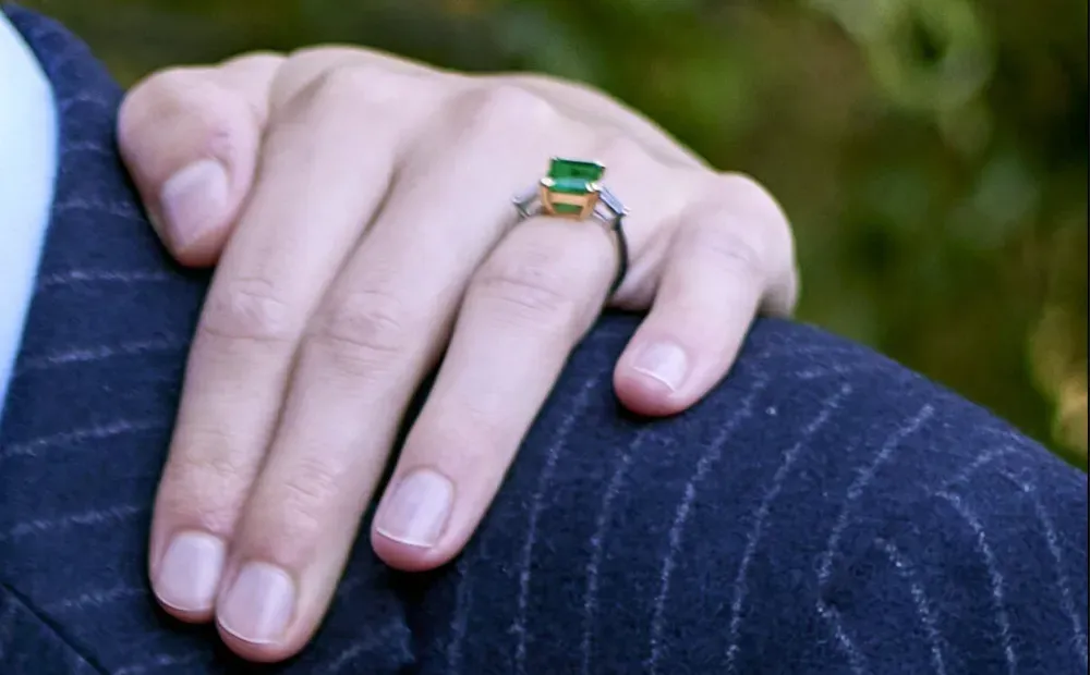Hand with green gemstone ring resting on a dark blue pinstriped suit jacket Hand with green gemstone ring resting on a dark blue pinstriped suit jacket