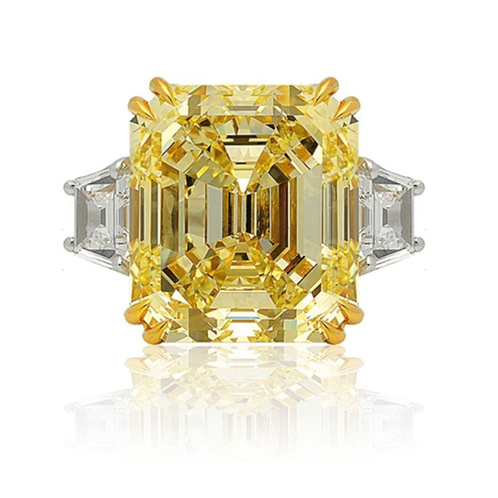 Yellow emerald-cut diamond ring with clear side stones on a white background