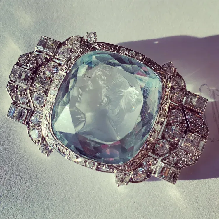 Silver jeweled ring with a large clear gemstone on a light surface, casting a shadow