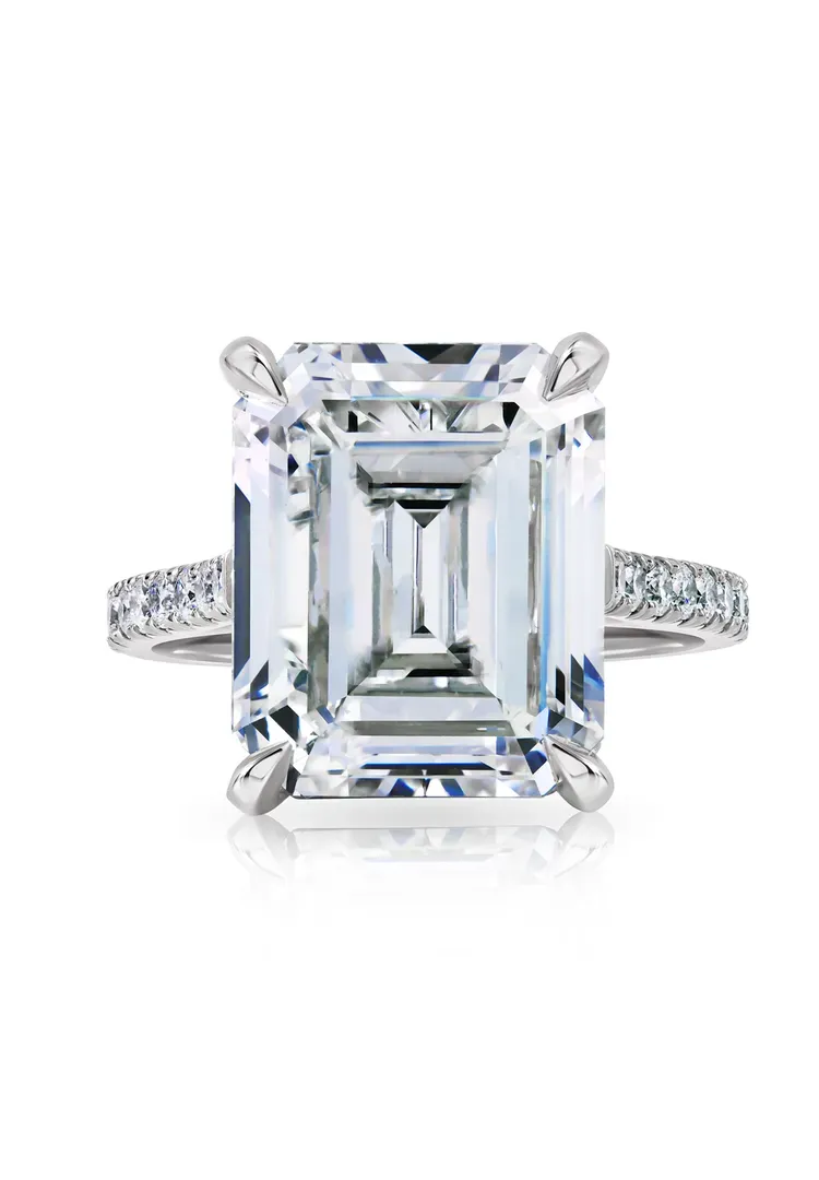 Emerald-cut diamond engagement ring with a pavé band on a white background Emerald-cut diamond engagement ring with a pavé band on a white background