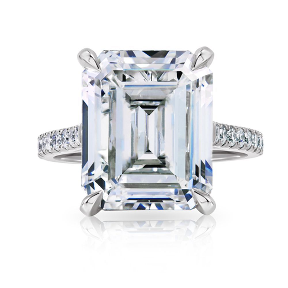 Emerald-cut diamond engagement ring with a pavé band on a white background