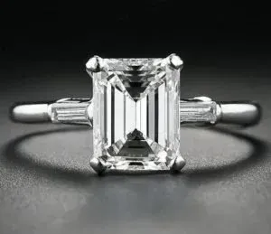 Emerald-cut diamond solitaire ring on a silver band against a dark background Emerald-cut diamond solitaire ring on a silver band against a dark background