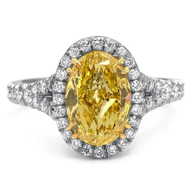 Oval yellow diamond engagement ring with a halo of clear diamonds on a silver band