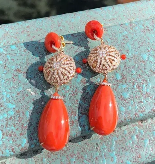 Red teardrop earrings with jeweled round tops on a turquoise textured surface. Red teardrop earrings with jeweled round tops on a turquoise textured surface.
