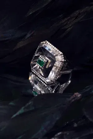 Diamond ring with a square halo setting on a dark, textured fabric background