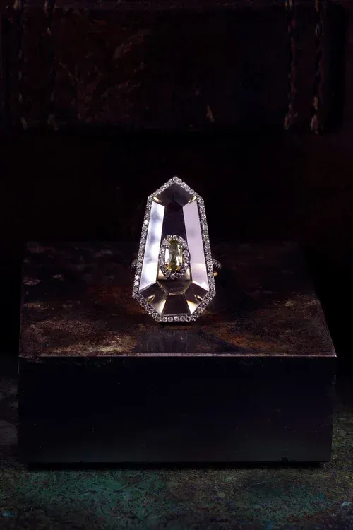 Faceted clear crystal sculpture on a dark pedestal against a black background