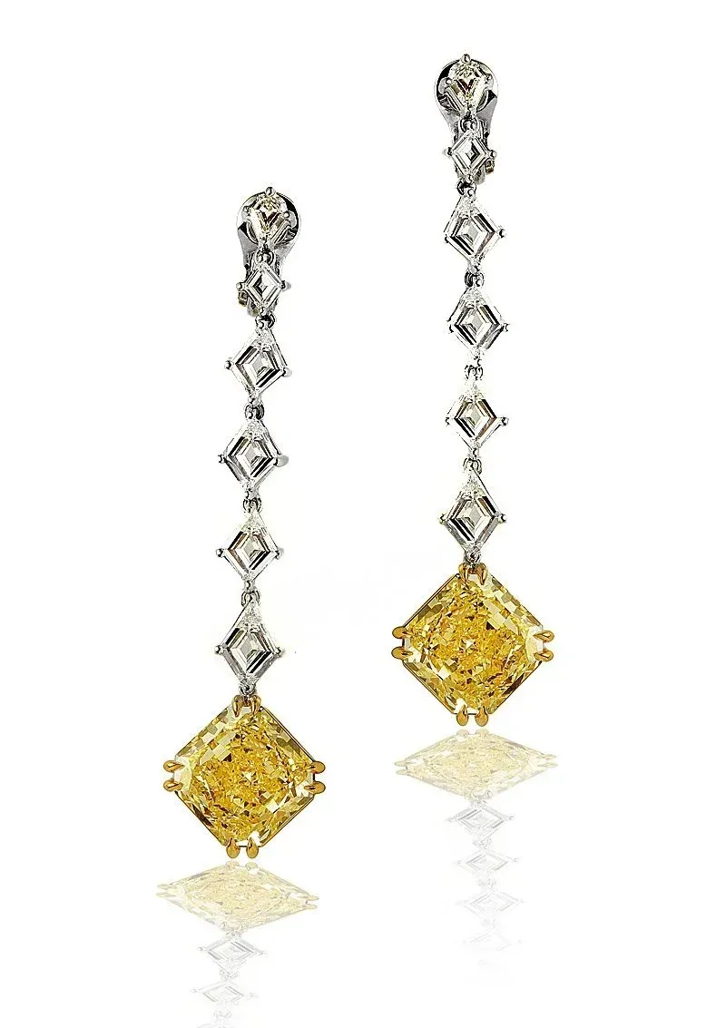 Pair of dangling earrings with silver and yellow diamond-shaped stones on a white background