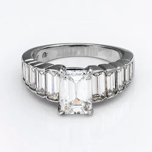 Silver ring with a rectangular center diamond and baguette side stones on a white background Silver ring with a rectangular center diamond and baguette side stones on a white background