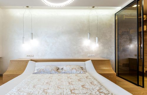 Modern bedroom with a large bed, white bedding, pendant lights, and wood-paneled bedside tables