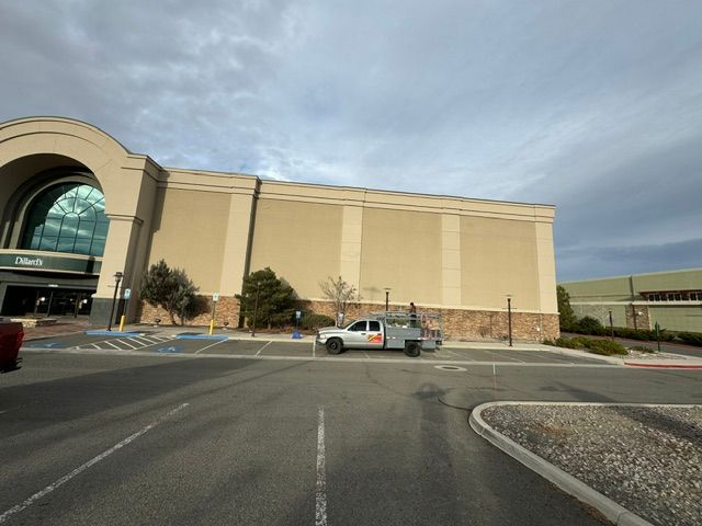 Large tan building with an arched entrance, a parked white truck, and an empty parking lot under cloudy skies